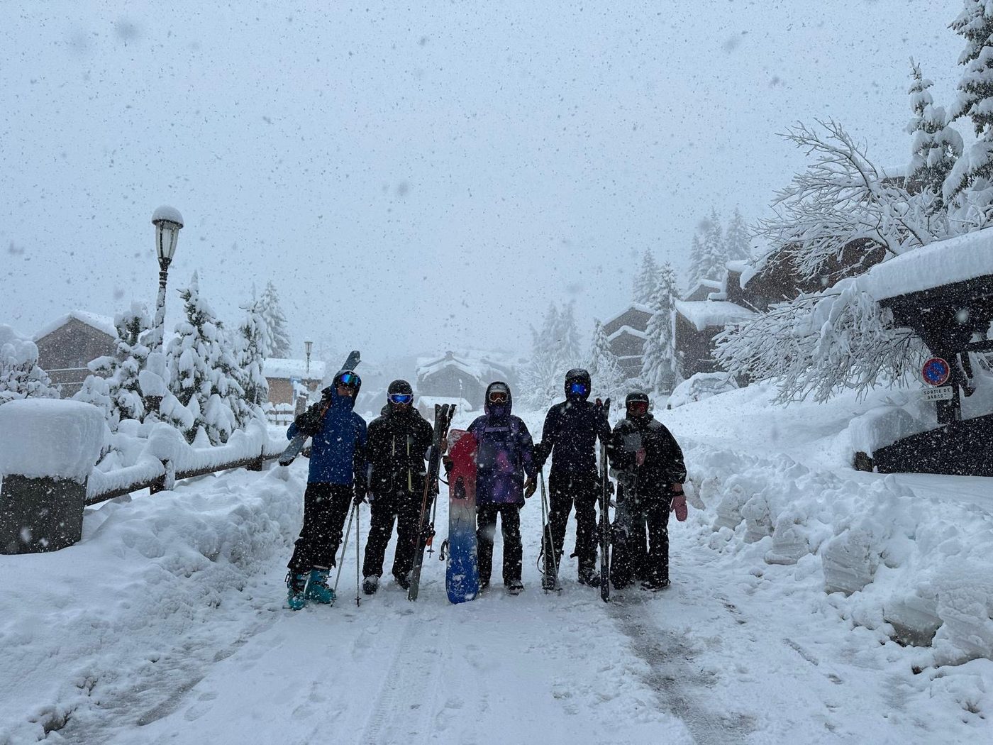 A group of skiers and snowboarders in an alpine village during heavy snowfall